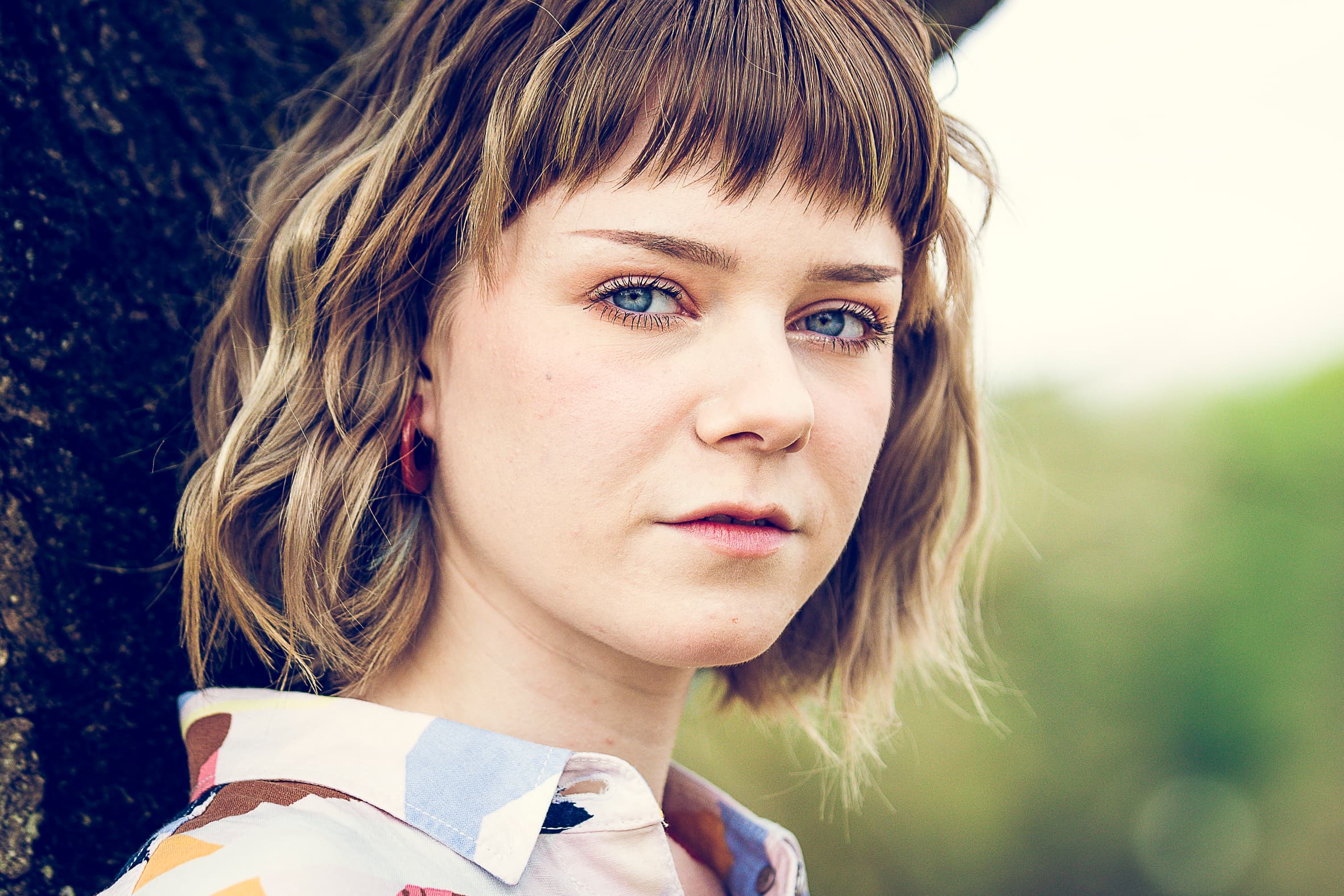 Ontspannen portret van een jonge vrouw tegen een oude boom tijdens een fotoshoot in Otterlo